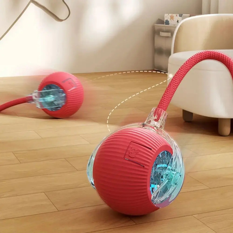Red robotic ball with a clear cover on a wooden floor, moving towards a white chair.