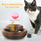 Cat playing with a cardboard toy structure with a built-in bell ball on a light gray background.