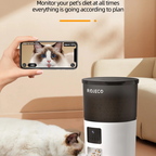 Person using a smartphone to monitor a cat with a ROJECO pet feeder in the background.
