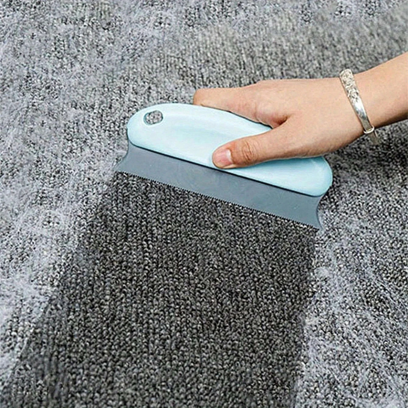 Hand using a blue carpet cleaning tool on a gray carpet