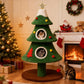 Green Christmas tree-shaped cat tree with two cats inside, in a cozy living room with a fireplace and decorated Christmas tree.
