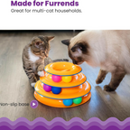 Two cats interacting with a three-tiered cat toy on a wooden floor.